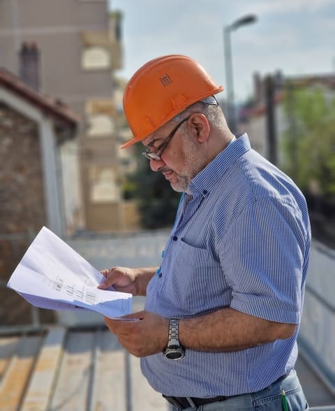 Gérard Jalloul, casque de chantier sur la tête, étudiant les plans d'un projet